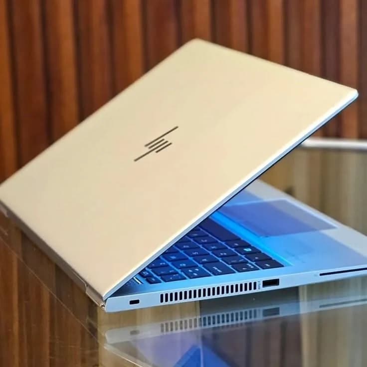 A gold HP laptop open on a reflective surface